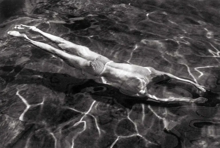 André Kertész fine art photography poster featuring a person swimming submerged in dark water with strong, geometric light reflections.