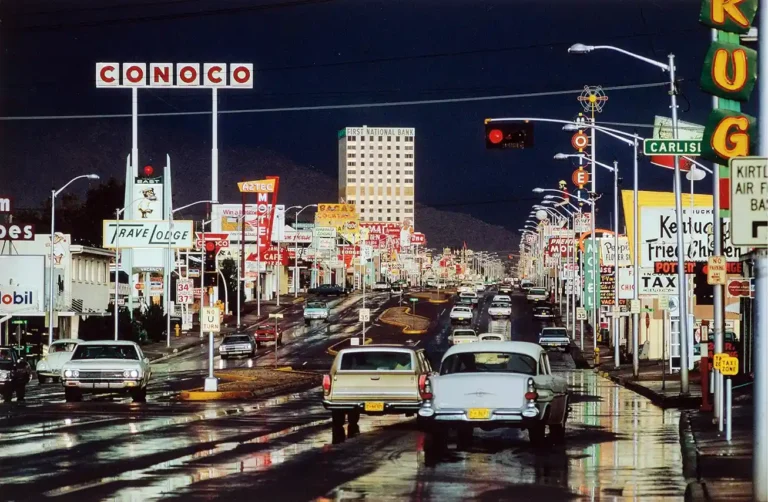 Ernst Haas photography poster featuring a busy Route 66 street scene in Albuquerque, NM, illuminated by colorful neon signs and wet asphalt reflections.