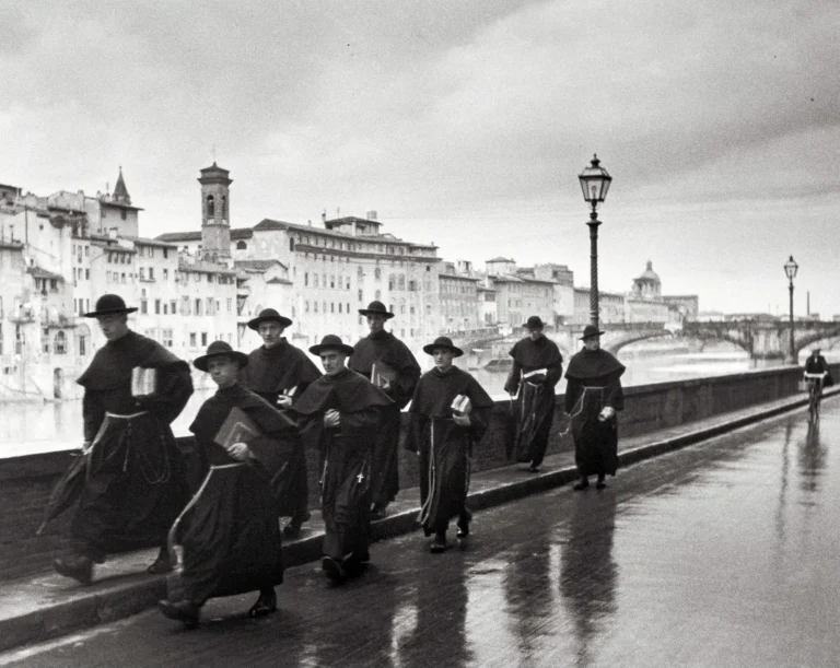 Alfred Eisenstaedt fine art photography poster featuring a group of monks walking along a reflective, rainy bridge in Florence, Italy, 1947.