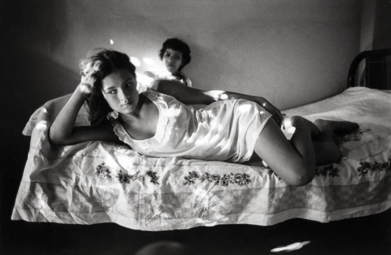 Danny Lyon fine art photography poster featuring a young woman lying on a bed in a sunlit black and white bedroom, El Paso, Texas, 1968.