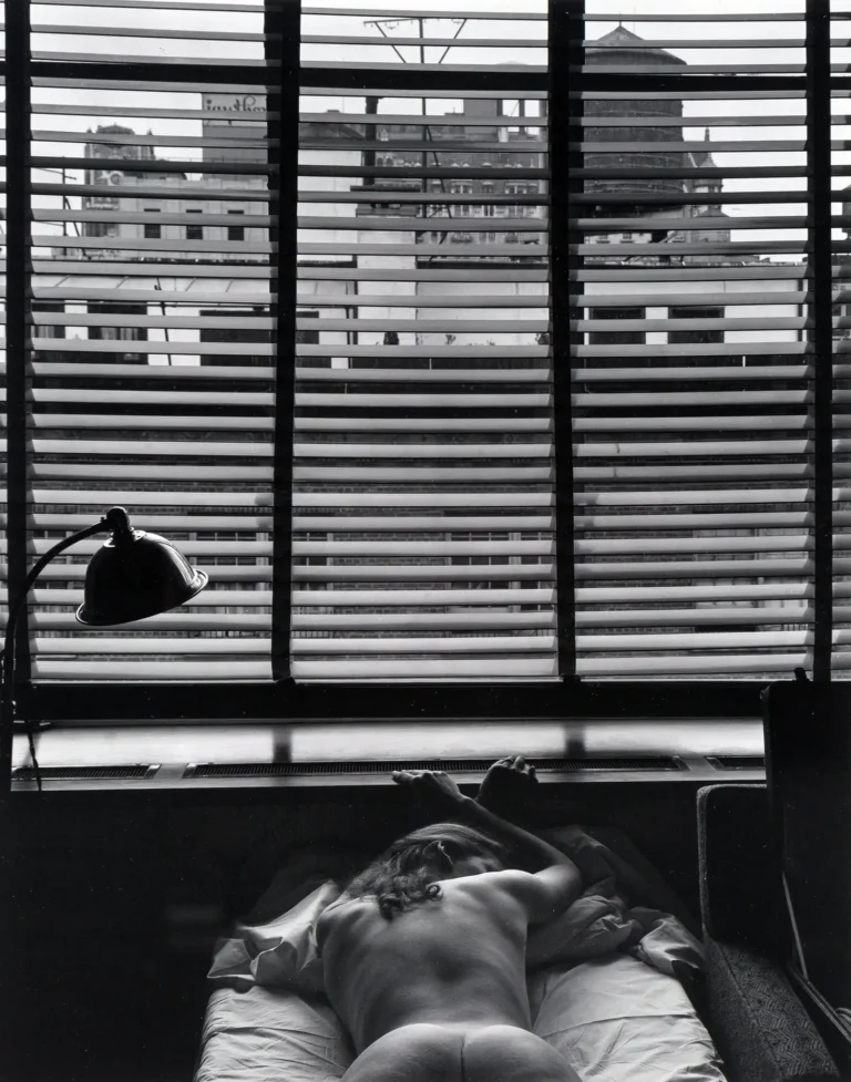 Edward Weston fine art photography poster featuring a nude figure lying in bed, seen through strong vertical and horizontal window blinds with a cityscape visible.