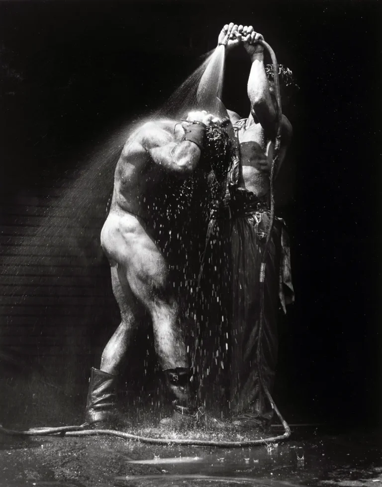 Herb Ritts Art Photography poster featuring two muscular male figures showering with a hose in high-contrast black and white against a dark background.
