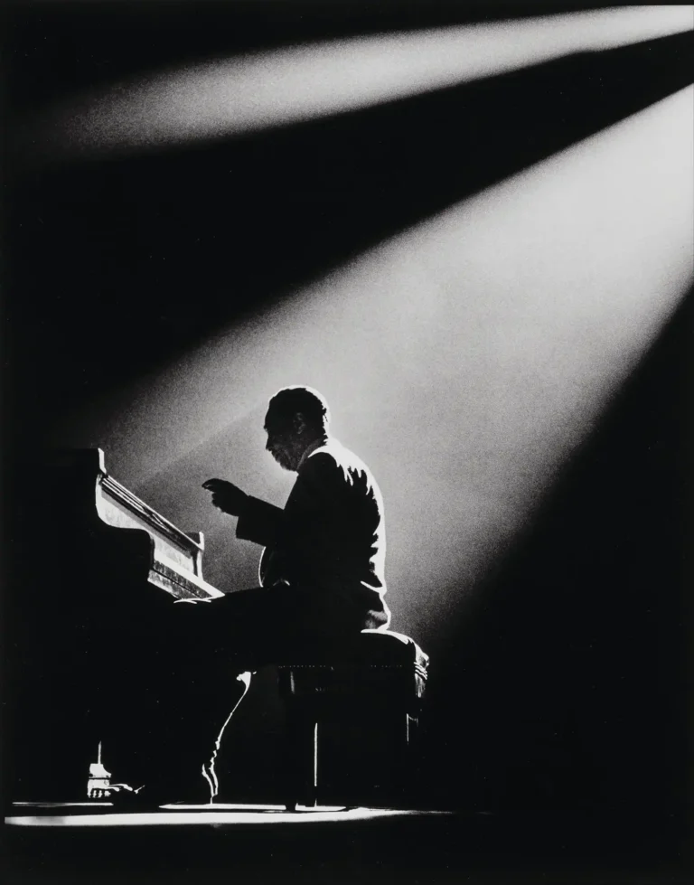 Duke Ellington Jazz Music poster by Herman Leonard featuring the pianist seated at a grand piano in a dramatic black and white spotlight silhouette.