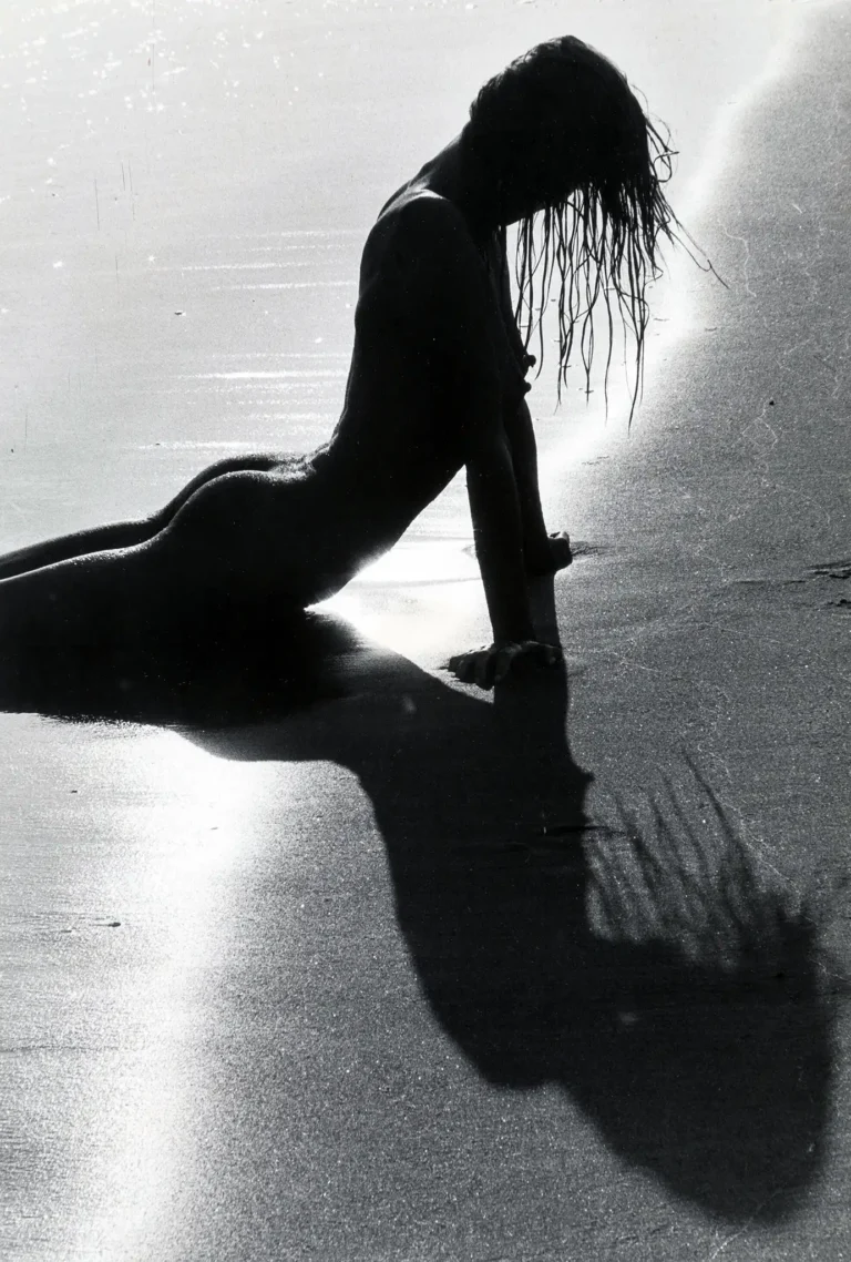 Lucien Clergue Fine Art Photography poster featuring a high-contrast black and white nude bather silhouette lying on a wet beach at sunset.