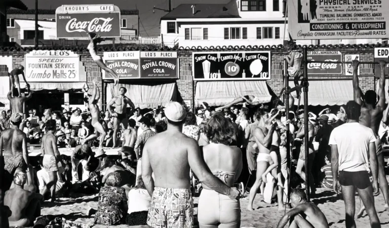Max Yavno fine art photography poster featuring a crowded, energetic black and white scene of gymnasts and strongmen performing acrobatics at Muscle Beach, Santa Monica in 1949.