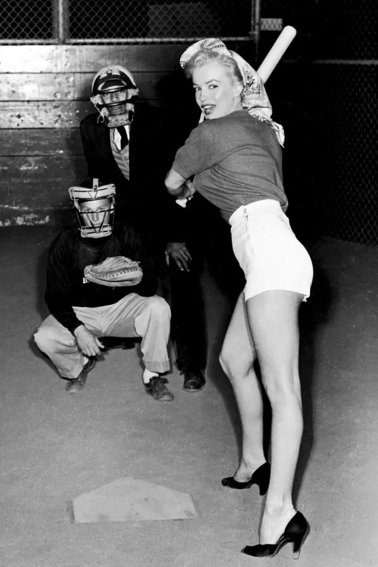 Marilyn Monroe Celebrity poster featuring her at bat in shorts and heels, with Chicago White Sox catcher, in a black and white vintage photo.