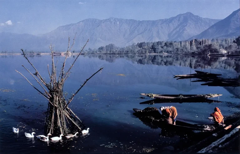 Raghubir Singh Art Photography poster featuring Dal Lake, Kashmir, with mountain reflections, ducks, and two figures in small boats on the water.