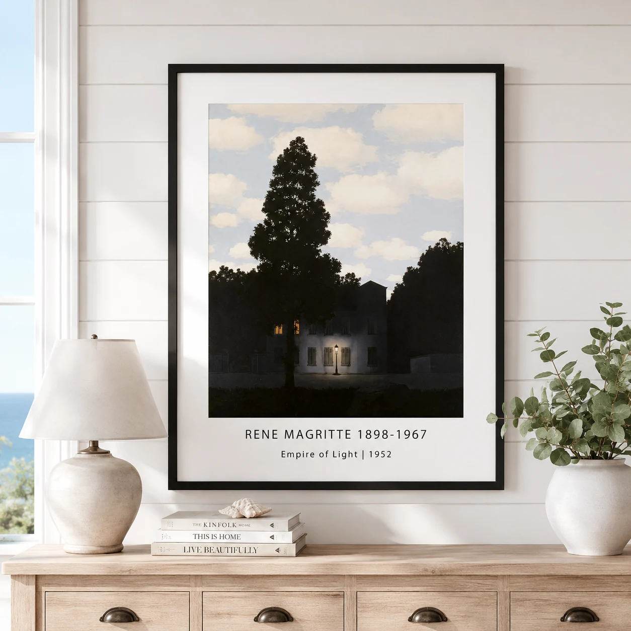 Room mockup of Empire of Light Print, Magritte Night House Wall Art Print, displayed as framed wall art in a living room setting as a portrait print with blue and white tones.