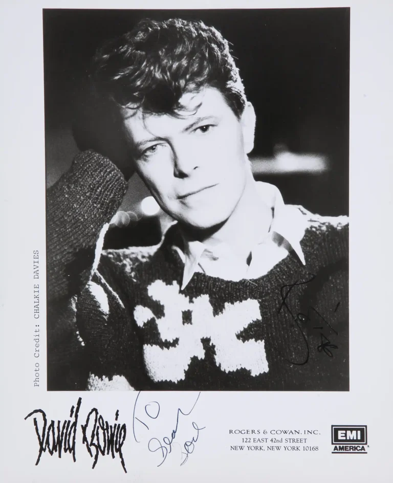 Clean artwork view of David Bowie EMI Promo Portrait by Chalkie Davies Photography Print. A classic black and white portrait of David Bowie wearing a patterned sweater, featuring a vintage EMI America logo and replica signatures in a matte finish.