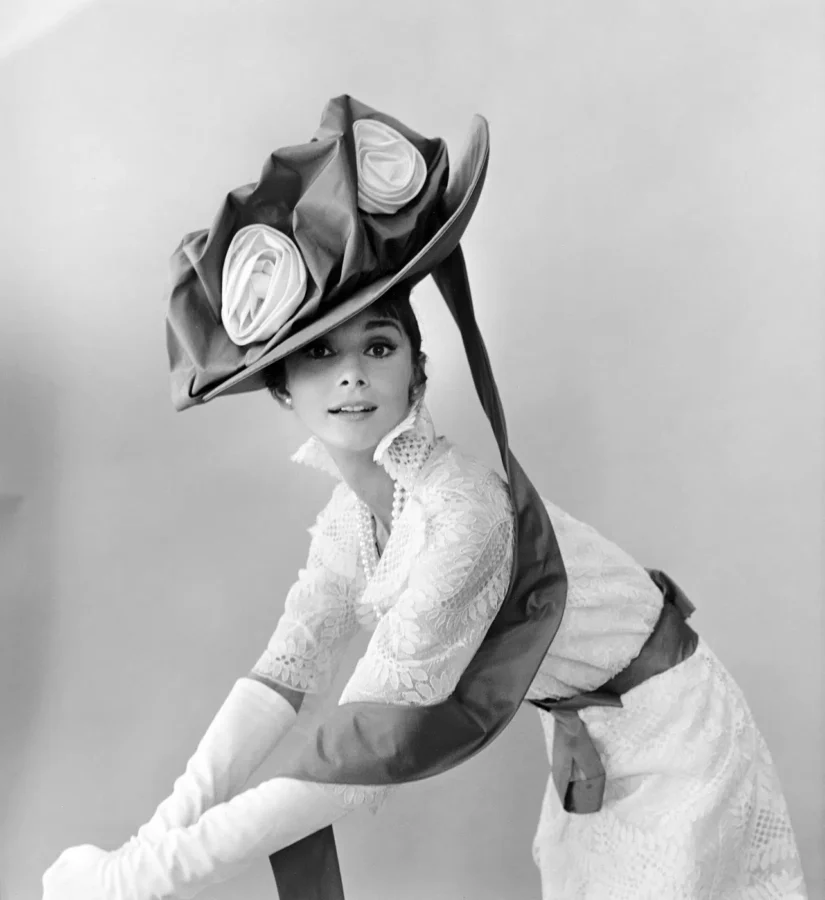Audrey Hepburn wearing an oversized floral hat and lace gown from My Fair Lady in a black and white photography print.