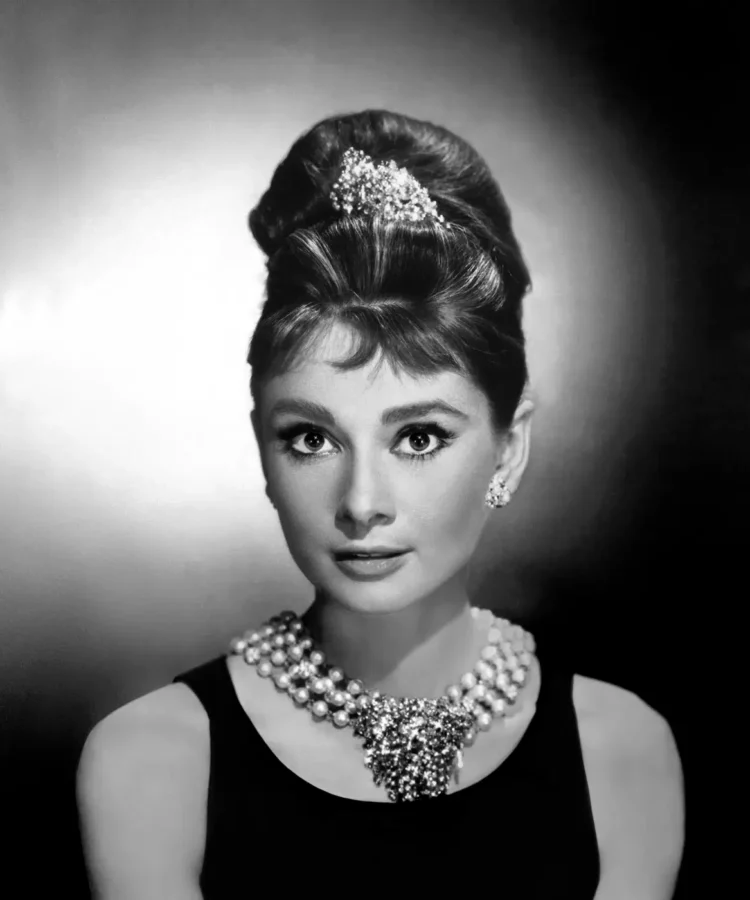 Audrey Hepburn in a black and white portrait from Breakfast at Tiffany's with a tiara and pearl necklace.