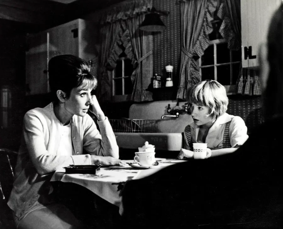 Black and white photography of Audrey Hepburn and Shirley MacLaine on the set of The Children's Hour in a 1961 kitchen scene.