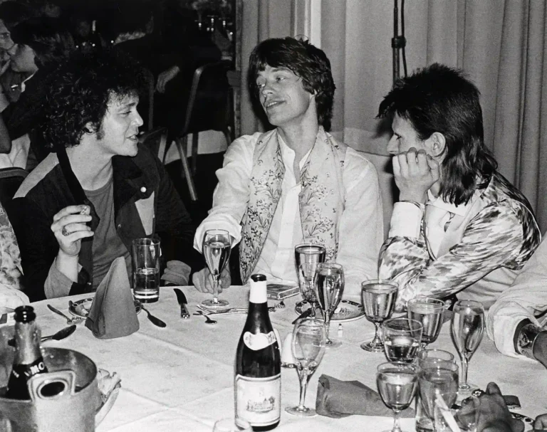 Clean artwork view of Lou Reed, Mick Jagger and David Bowie at Cafe Royale Photography Print. A candid black and white photograph featuring Lou Reed, Mick Jagger, and David Bowie during the Ziggy Stardust farewell party at London's Cafe Royale.