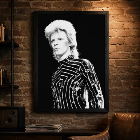 A framed David Bowie concert poster hanging on a minimalist living room wall above a modern credenza.