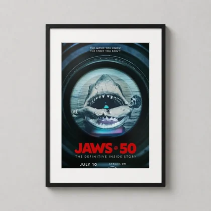 A framed Jaws 50 documentary art print hanging on a dark wall in a modern home cinema room.