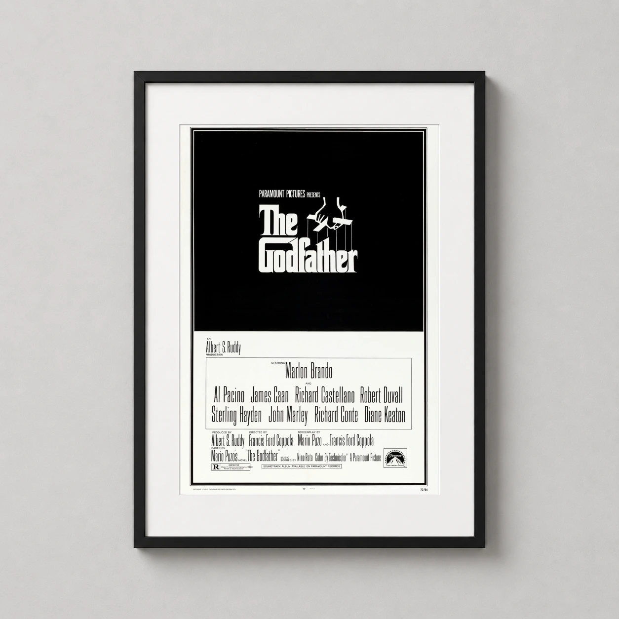 Room mockup of The Godfather 1972 Classic Movie Puppet Strings Logo Movie Poster, displayed as framed wall art in a home theater setting as a portrait print with black and white tones.