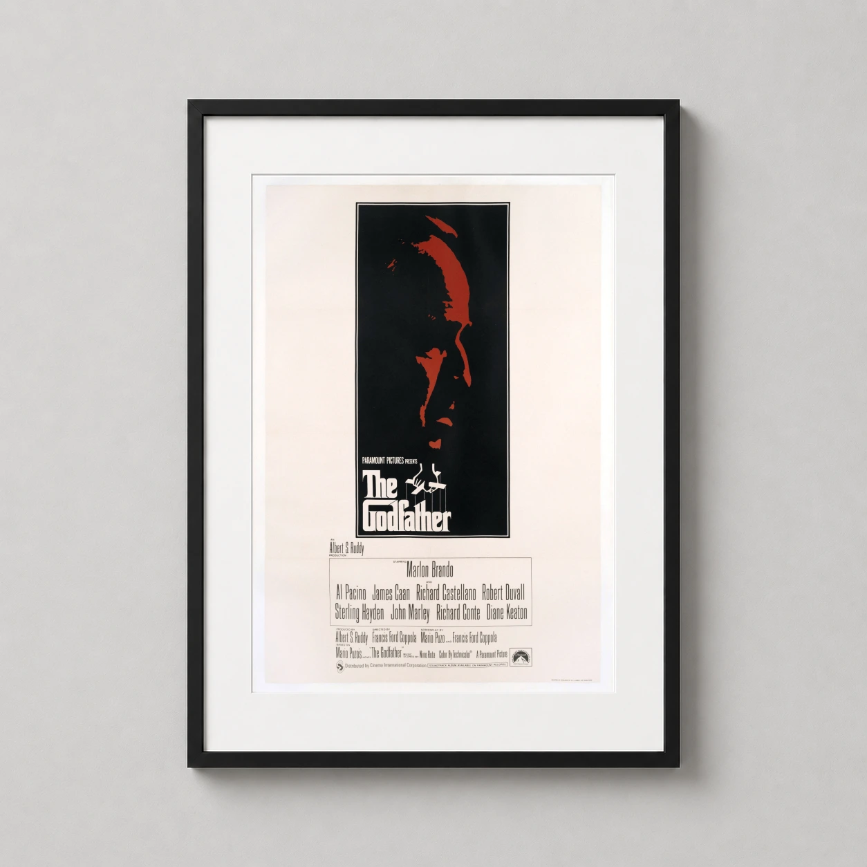 Room mockup of The Godfather Marlon Brando Profile Minimalist Movie Poster, displayed as framed wall art in a home theater setting as a portrait print with red and black tones.
