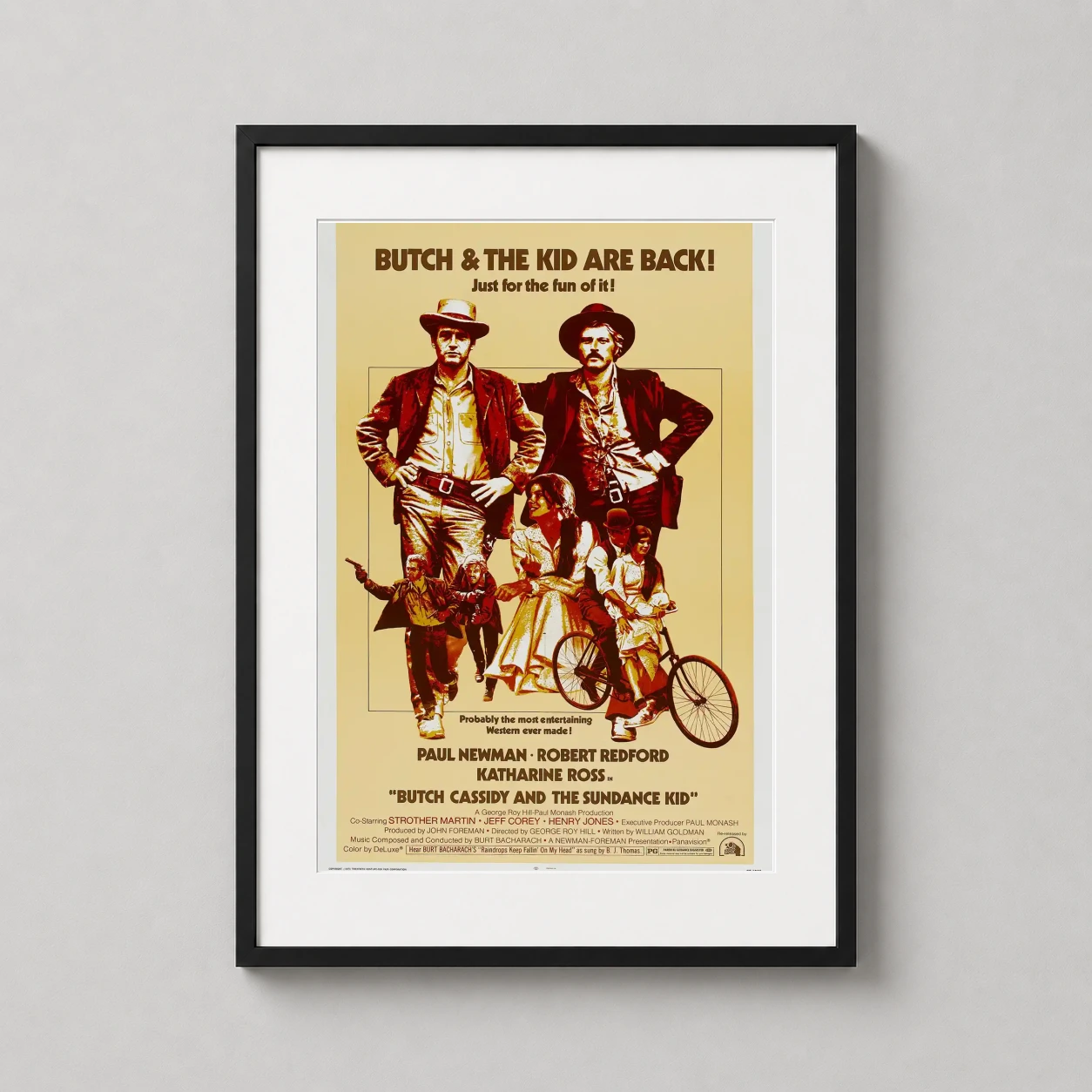 Room mockup of Butch Cassidy and the Sundance Kid Movie Poster, displayed as framed wall art in a home theater setting as a portrait print with gold tones.