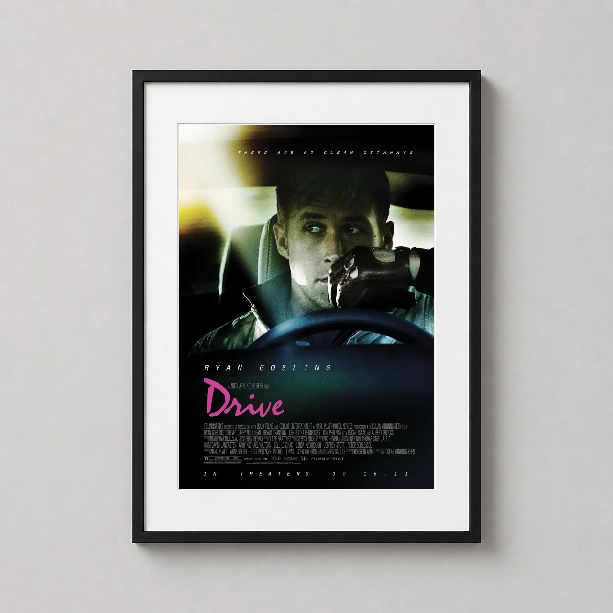 Room mockup of Drive Movie Ryan Gosling Driver with Gloves Poster Movie Poster, displayed as framed wall art in a home theater setting as a portrait print with green and pink tones.