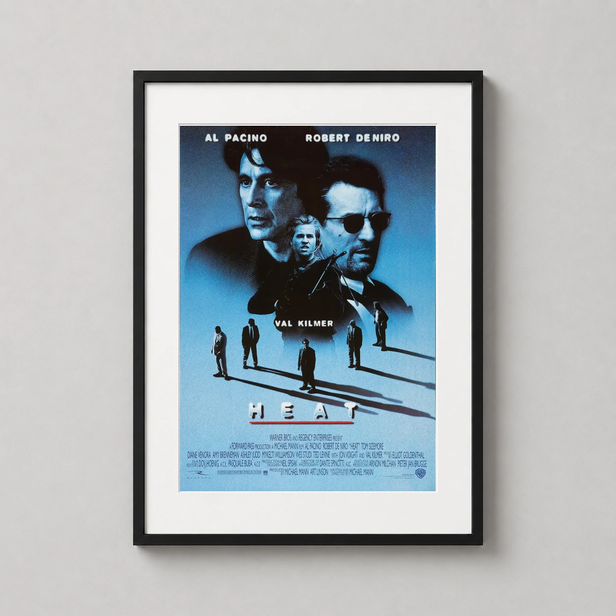 Room mockup of Heat Al Pacino and Robert De Niro Film Poster, displayed as framed wall art in a home theater setting as a portrait print with blue, red, and grey tones.