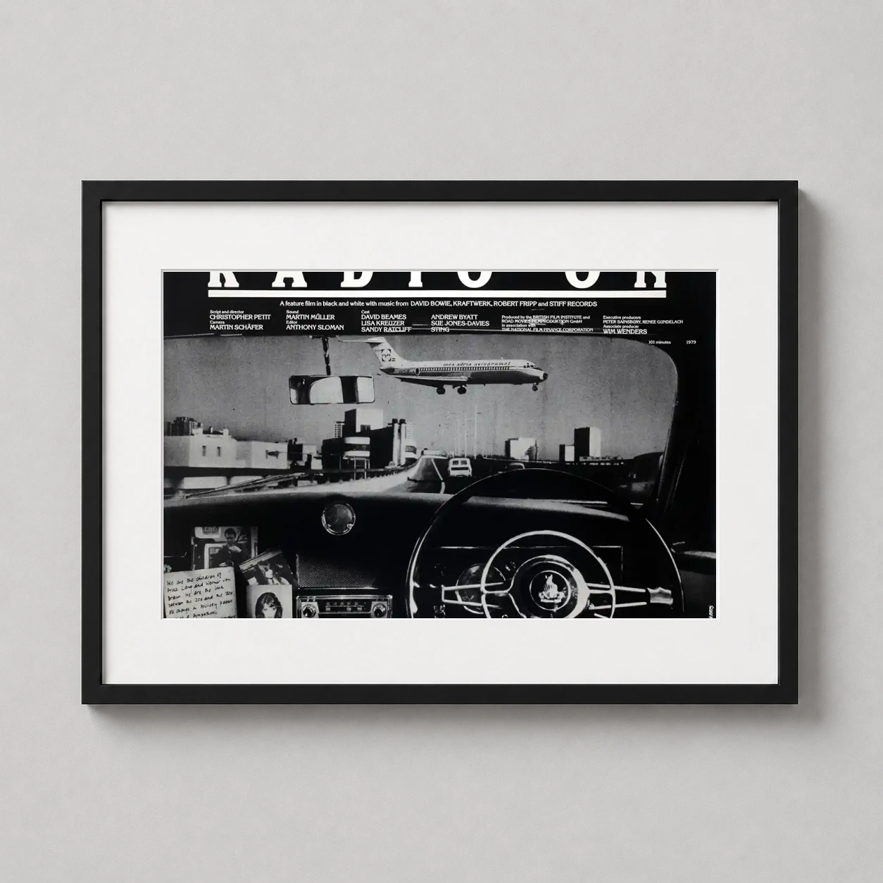 Room mockup of Radio On 1979 Cinematic Road Trip Movie Poster, displayed as framed wall art in a home theater setting as a landscape print with black and white tones.