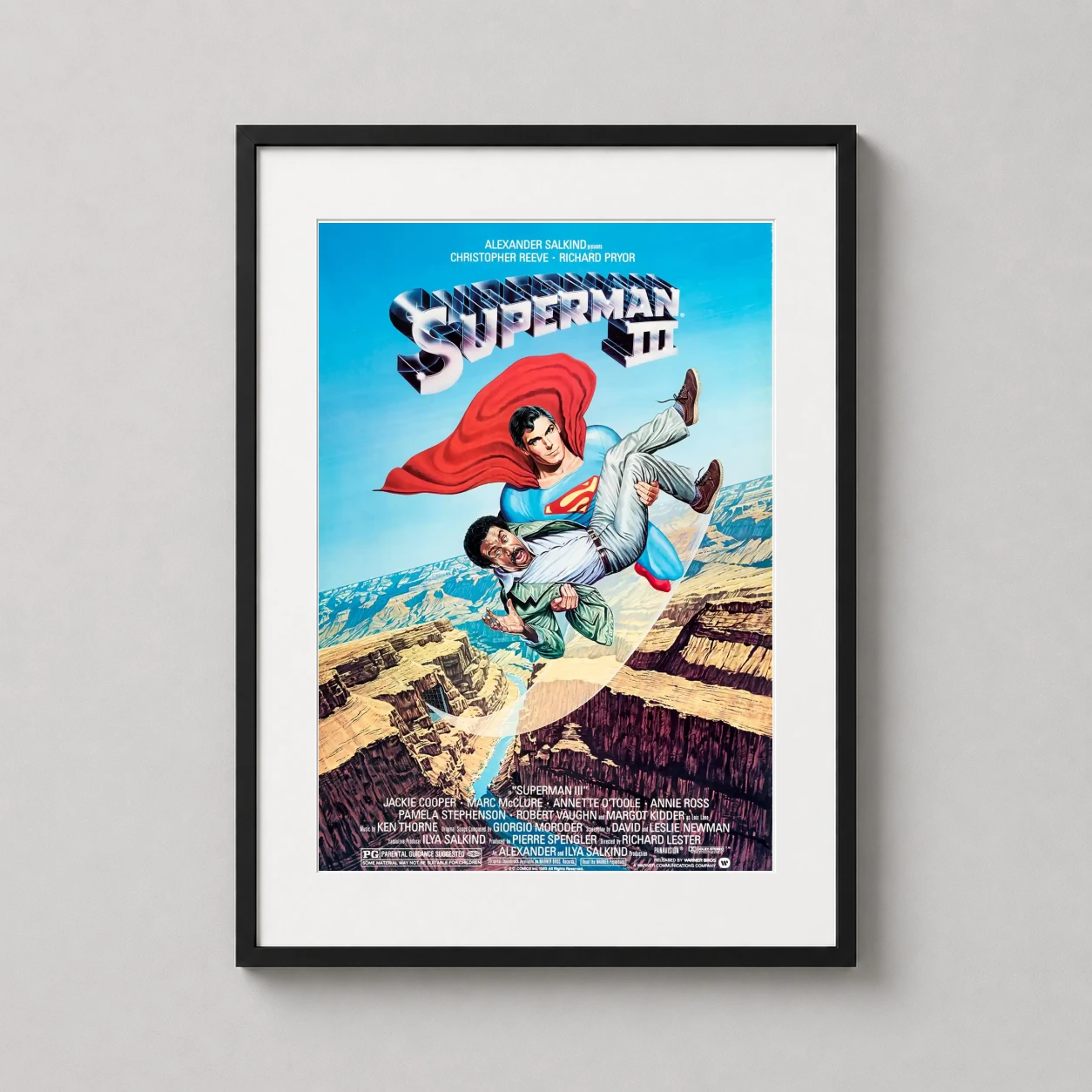Room mockup of Superman III Richard Pryor and Christopher Reeve Print Movie Poster, displayed as framed wall art in a home theater setting as a portrait print with blue tones.