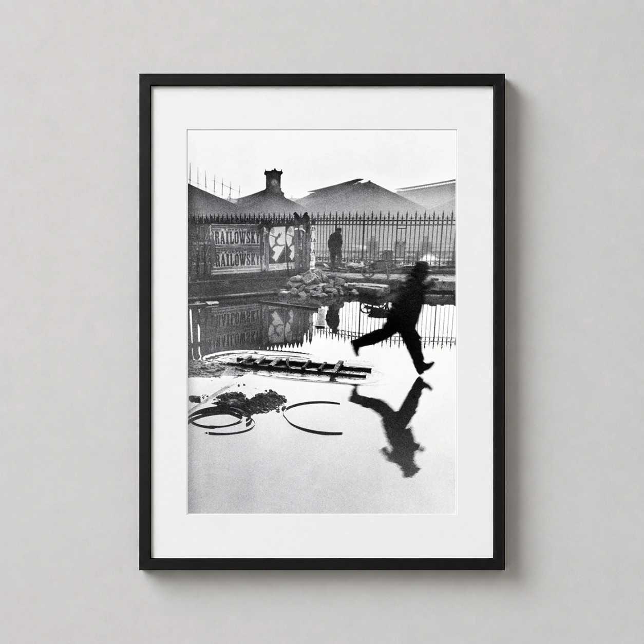 Henri Cartier-bresson Behind Gare — grainy black and white photography print capturing a man leaping over a
