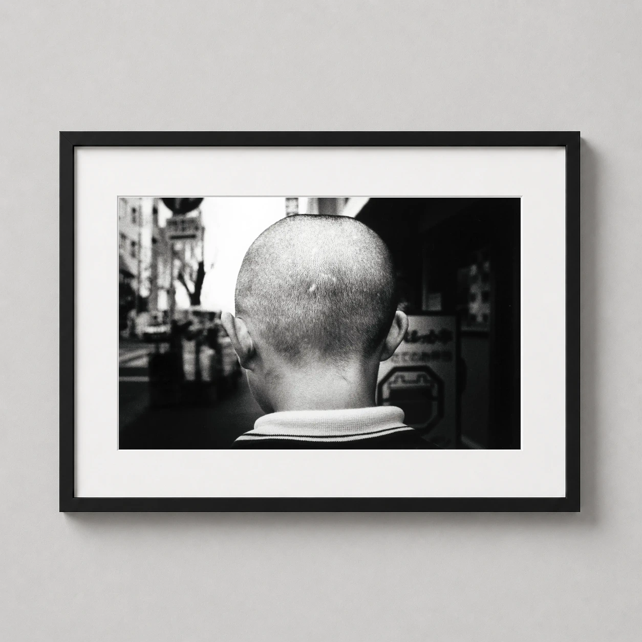 Room mockup of Daido Moriyama, Tokyo Back of Boys Head 1981 Photography Print, displayed as framed wall art in a office setting as a landscape print with black and white tones.