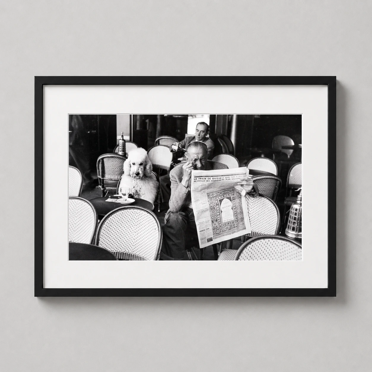 Room mockup of Café de Flore 1953 by Edouard Boubat Paris Photography Print, displayed as framed wall art in a office setting as a landscape print with black and white tones.