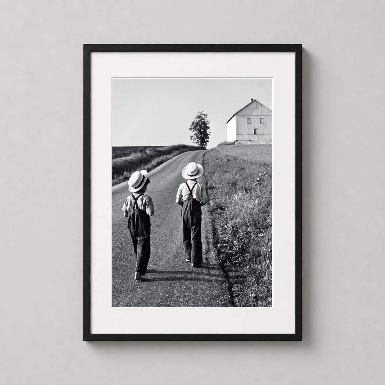 Room mockup of George Tice Amish Boys Lancaster Pennsylvania 1962 Photography Print, displayed as framed wall art in a office setting as a portrait print with black and white tones.