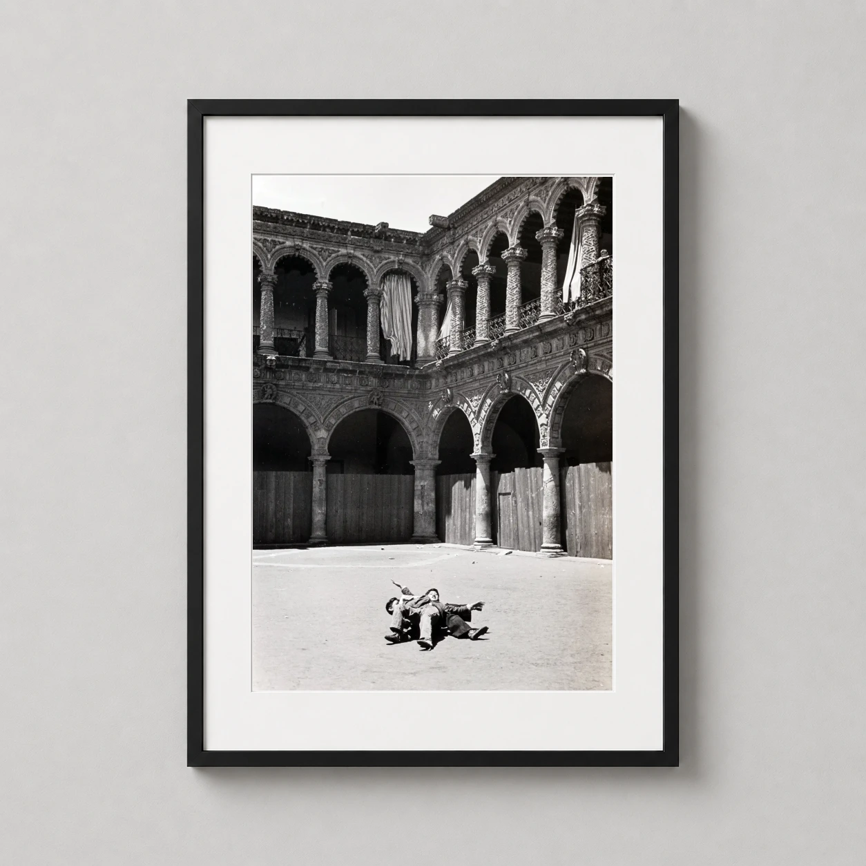 Room mockup of Helen Levitt Mexico Courtyard 1941 Photography Print, displayed as framed wall art in a office setting as a portrait print with black and white tones.