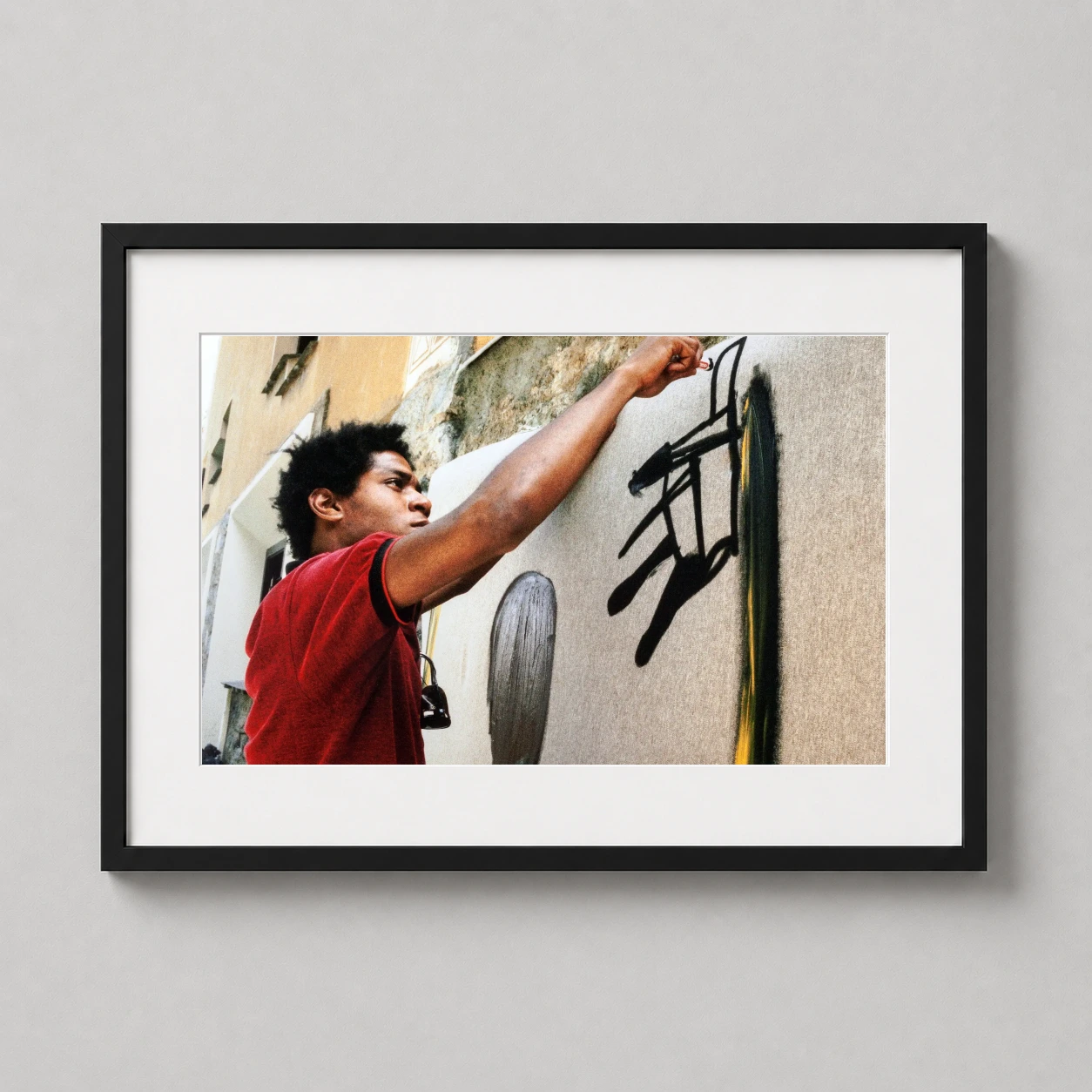 Jean Michel Basquiat Painting — candid color photograph of artist Jean-Michel Basquiat in a red shirt