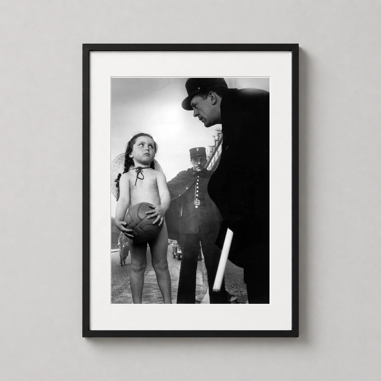 Robert Doisneau Printemps Girl — young girl holds a leather ball while standing before two French