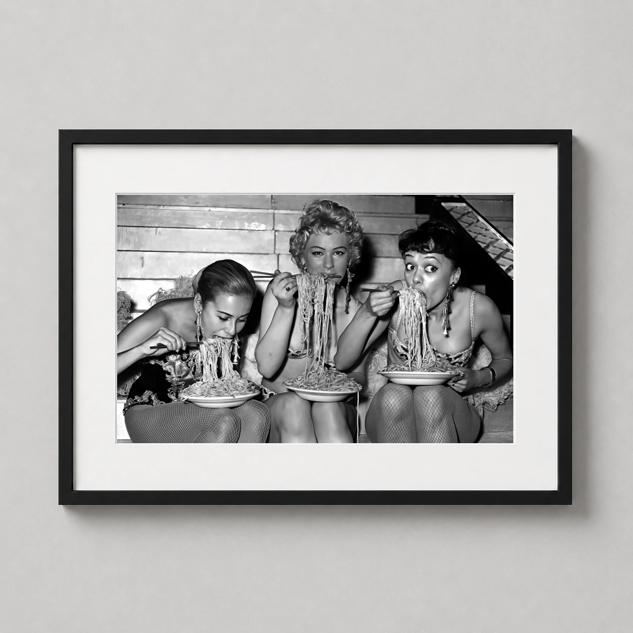 Room mockup of Women Eating Spaghetti Vintage Black and White Photography Print, displayed as framed wall art in a office setting as a landscape print with black and white tones.