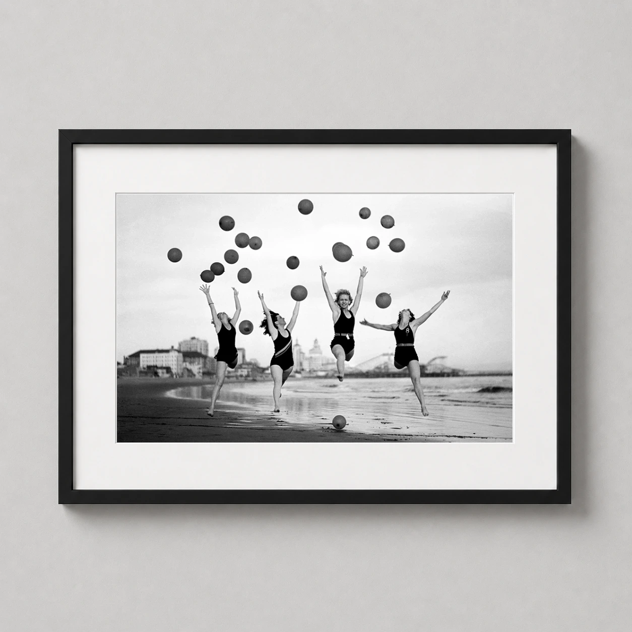 Room mockup of Vintage Beach Girls with Balloons Black and White Photography Print, displayed as framed wall art in a office setting as a landscape print with black and white tones.