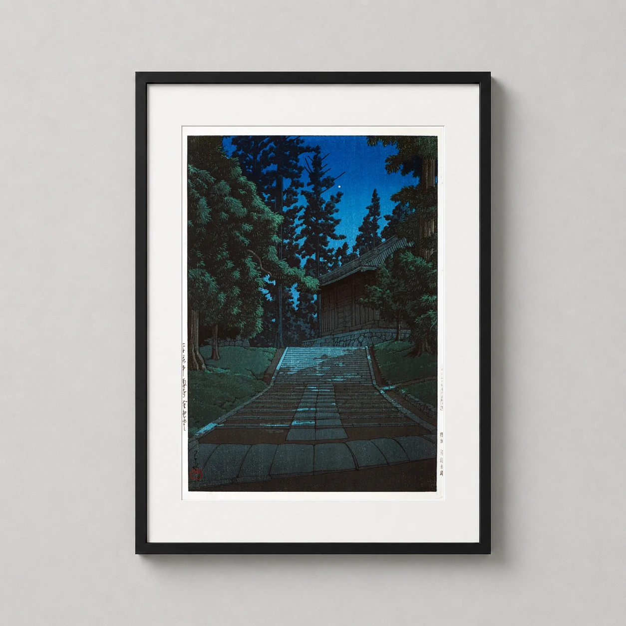 Room mockup of Hasui Kawase Hiraizumi Chusonji Temple Night Scene Art Print, displayed as framed wall art in a bedroom setting as a portrait print with blue tones.