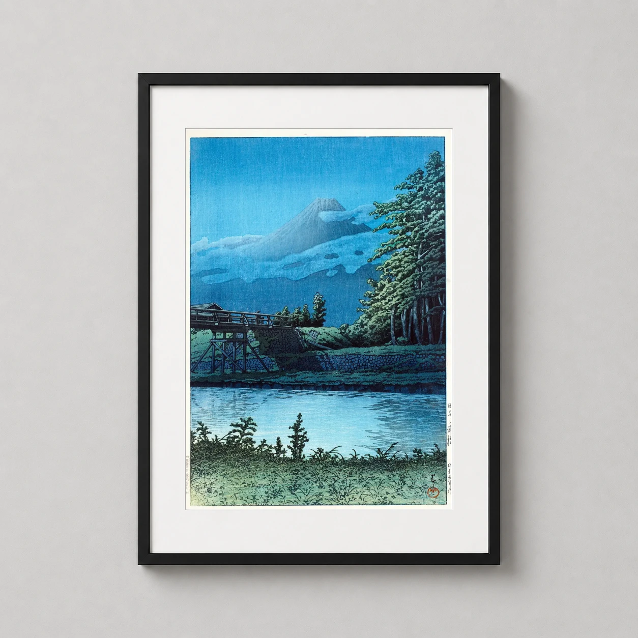 Room mockup of Tagonoura Bridge and Mount Fuji Japanese Woodblock Art Print, displayed as framed wall art in a bedroom setting as a portrait print with blue tones.