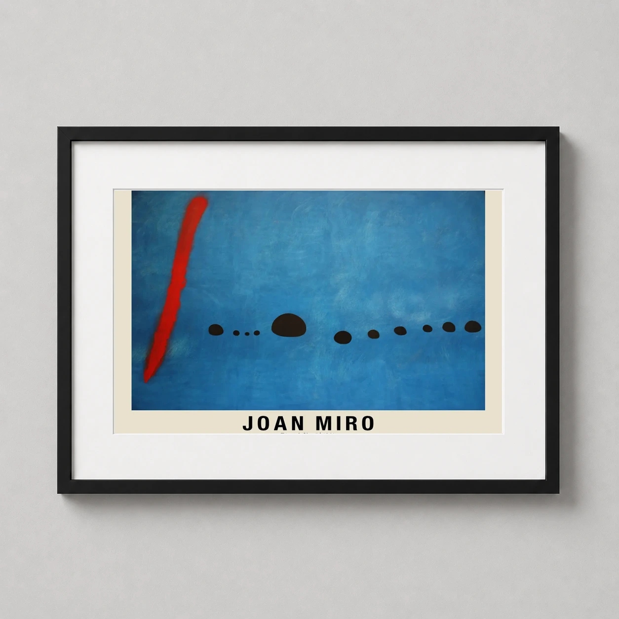Room mockup of Joan Miro Bleu II 1961 Abstract Surrealist Modern Art Print, displayed as framed wall art in a living room setting as a landscape print with blue, red, and black tones.