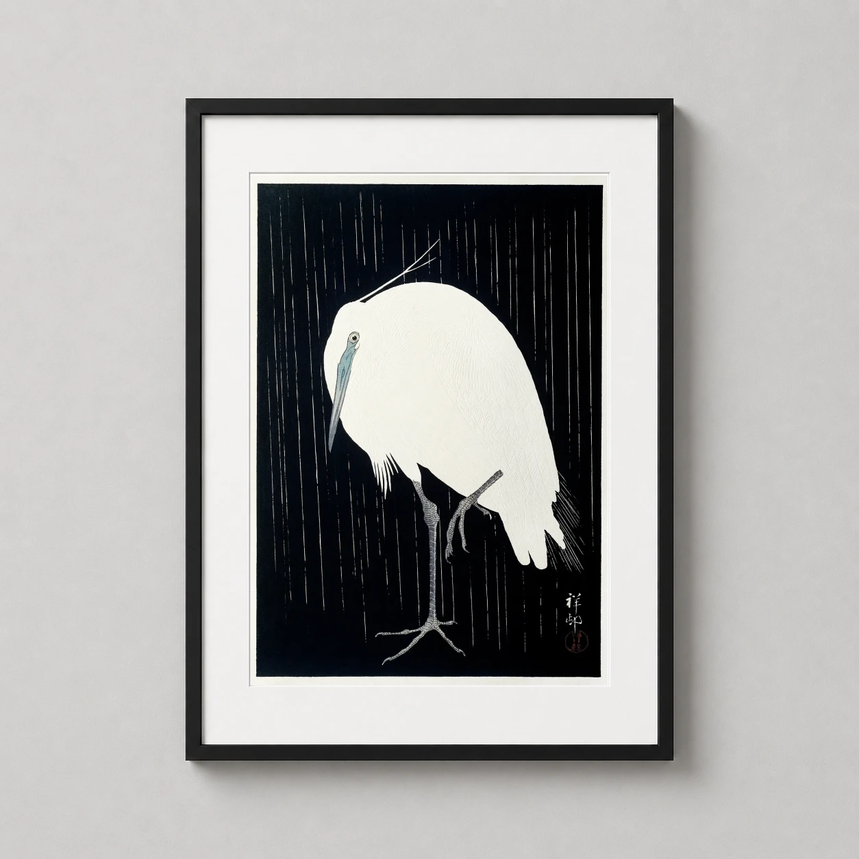 Room mockup of Egret in the Rain Japanese Woodblock Art Print, Ohara Koson, displayed as framed wall art in a bedroom setting as a portrait print with black and white tones.