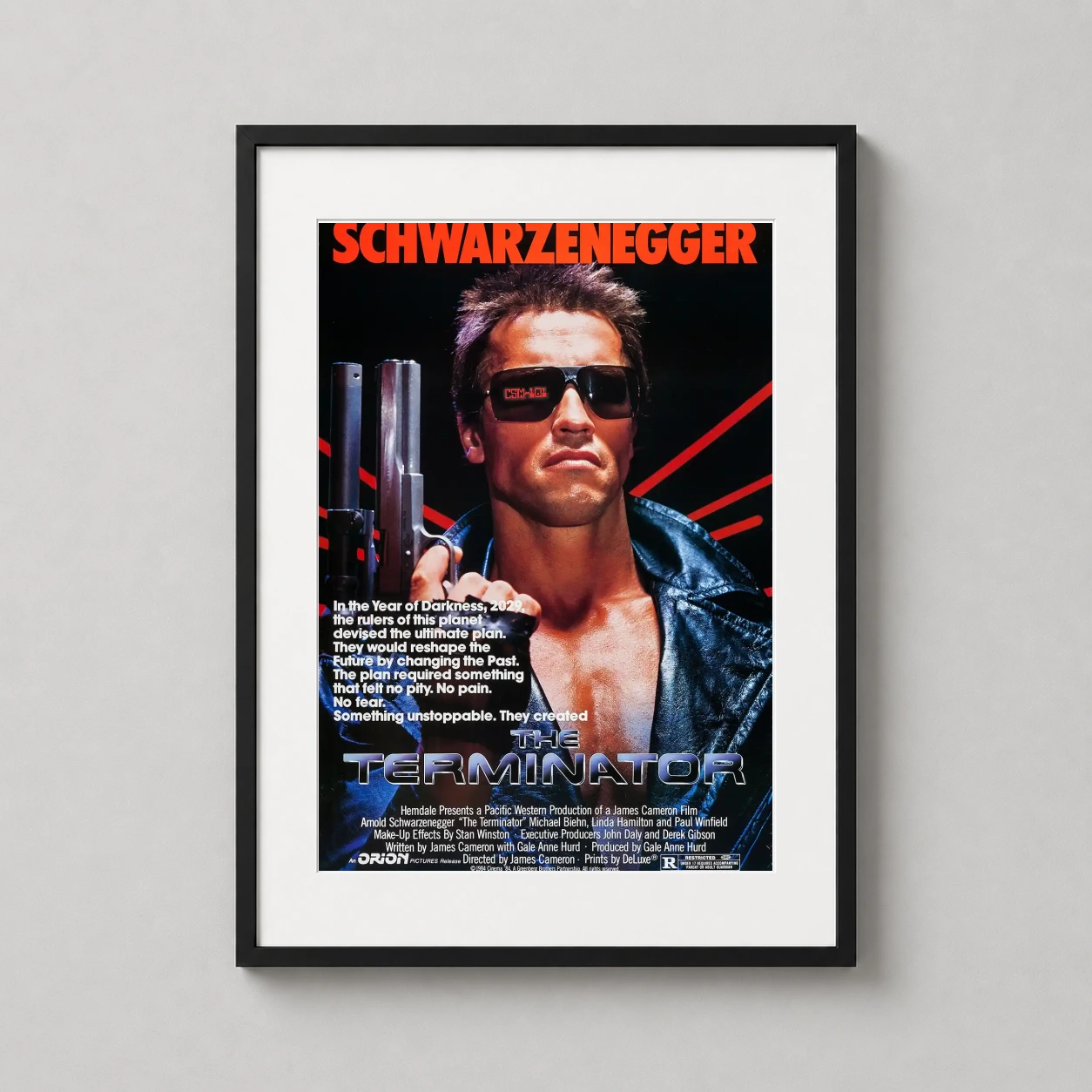 Room mockup of The Terminator 1984 Schwarzenegger Movie Poster, displayed as framed wall art in a home theater setting as a portrait print with blue and red tones.