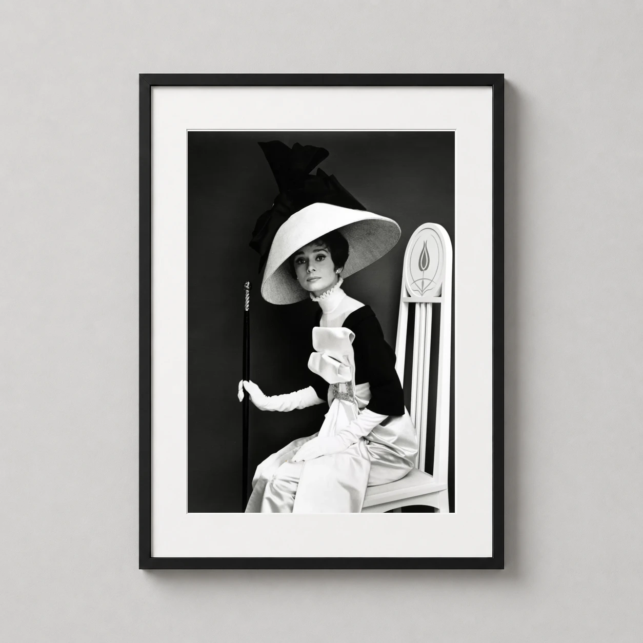 Room mockup of Audrey Hepburn Eliza Doolittle My Fair Lady High Fashion Photography Print, displayed as framed wall art in a home theater setting as a portrait print with black and white and gold tones.