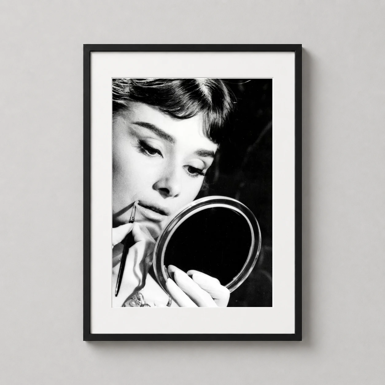 Room mockup of Audrey Hepburn Rome 1955 War and Peace Set Photography Print, displayed as framed wall art in a office setting as a portrait print with black and white and gold tones.