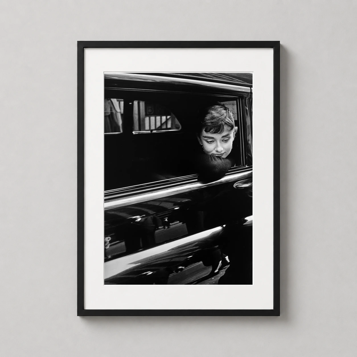 Room mockup of Audrey Hepburn Sabrina 1953 Car Window Photography Print, displayed as framed wall art in a office setting as a portrait print with black and white and gold tones.