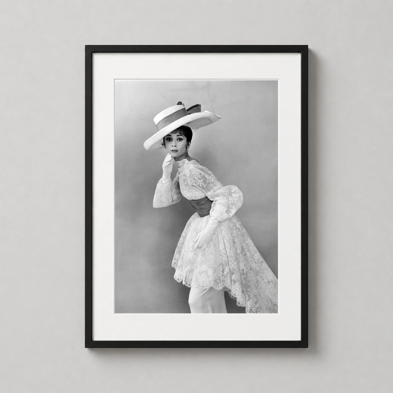 Room mockup of Audrey Hepburn 1963 Lace Dress and Wide Brim Hat Portrait Photography Print, displayed as framed wall art in a home theater setting as a portrait print with black and white tones.