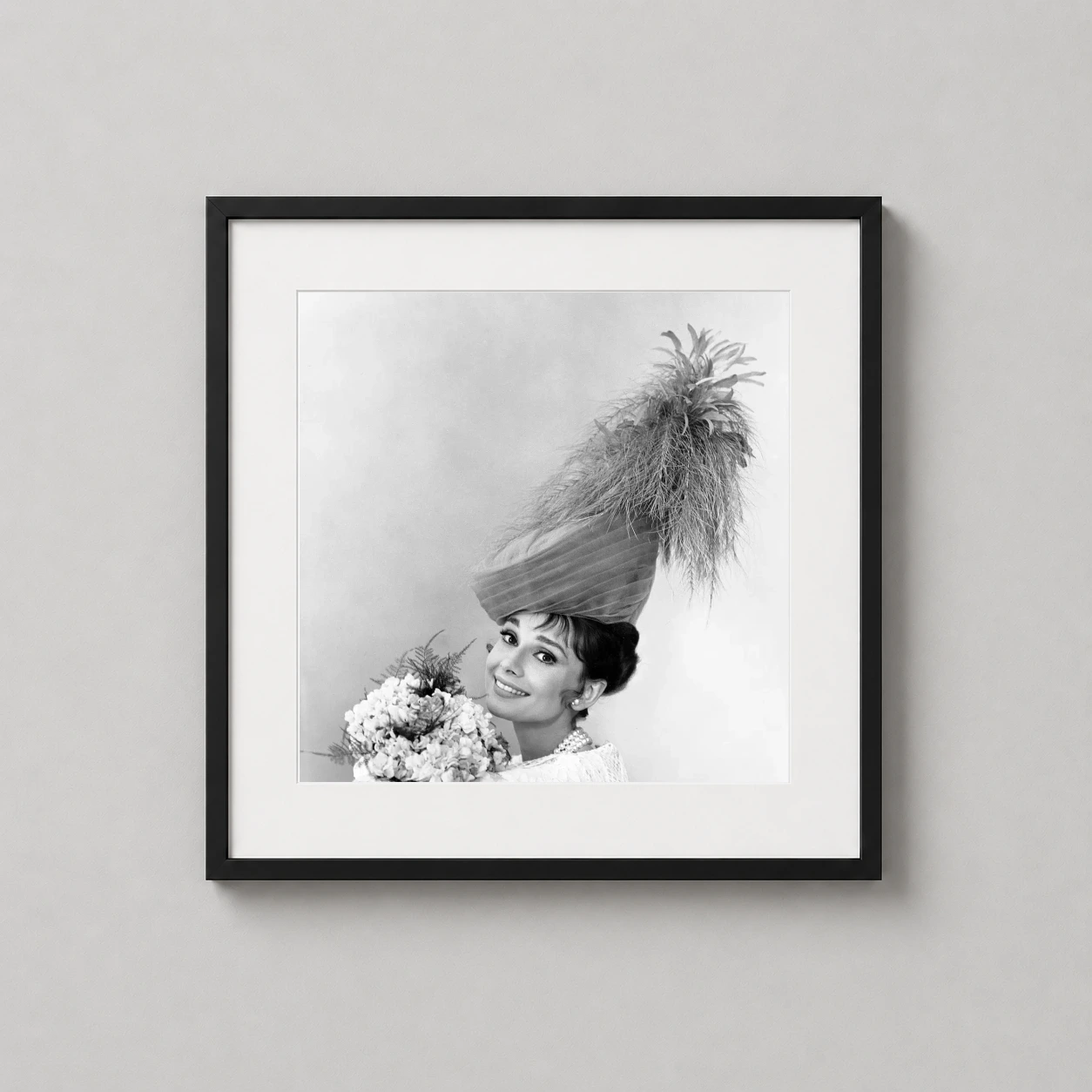 Room mockup of Audrey Hepburn 1963 Feathered Hat Gallery Portrait Photography Print, displayed as framed wall art in a home theater setting as a square print with black and white and gold tones.