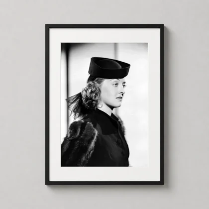 A framed Bette Davis portrait art print displayed on a modern office wall above a dark wooden desk.