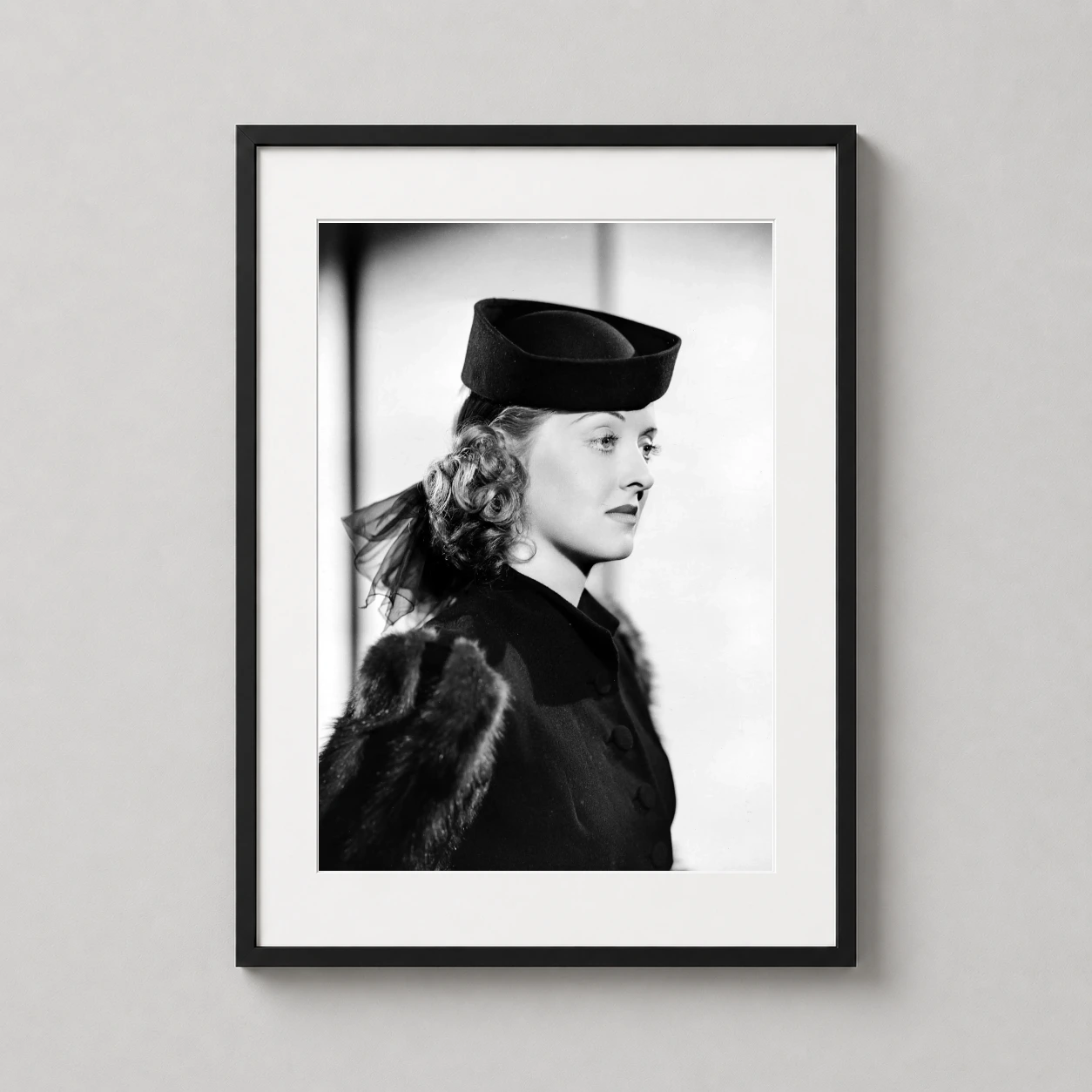 Room mockup of Bette Davis 1939 Warner Brothers Profile Portrait Photography Print, displayed as framed wall art in a office setting as a portrait print with black and white and gold tones.