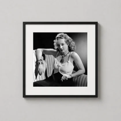 A framed Bette Davis glamour print hangs on a neutral wall in a sophisticated home library.