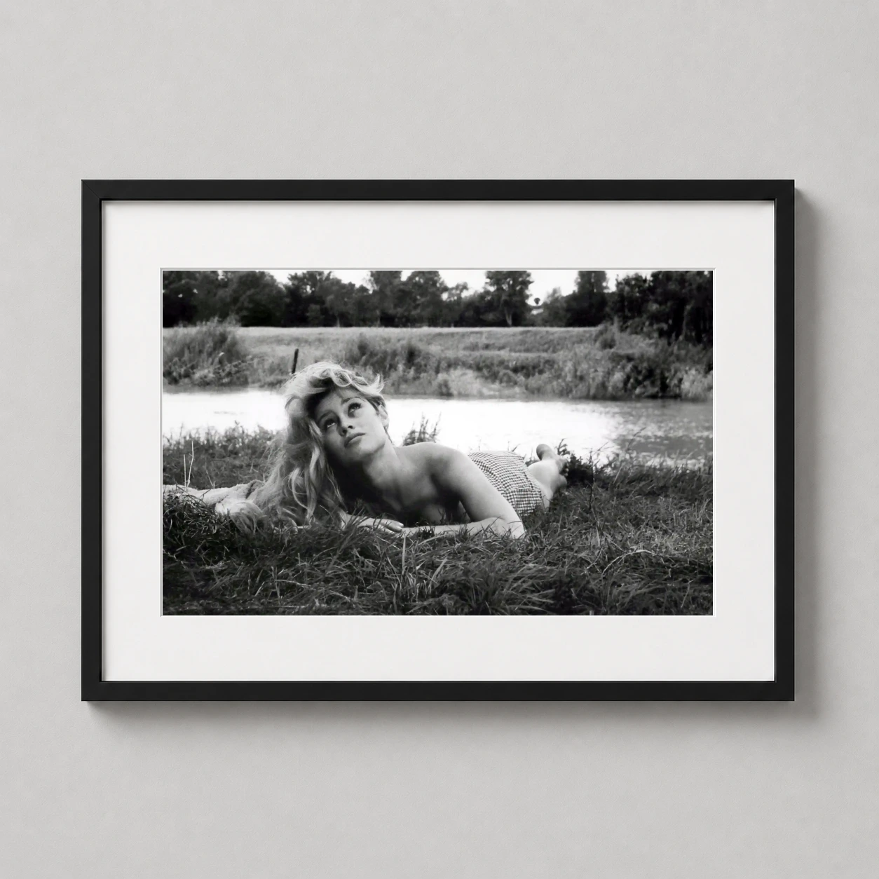 Brigitte Bardot Lying Grass — serene black and white photograph of Brigitte Bardot resting in a lush