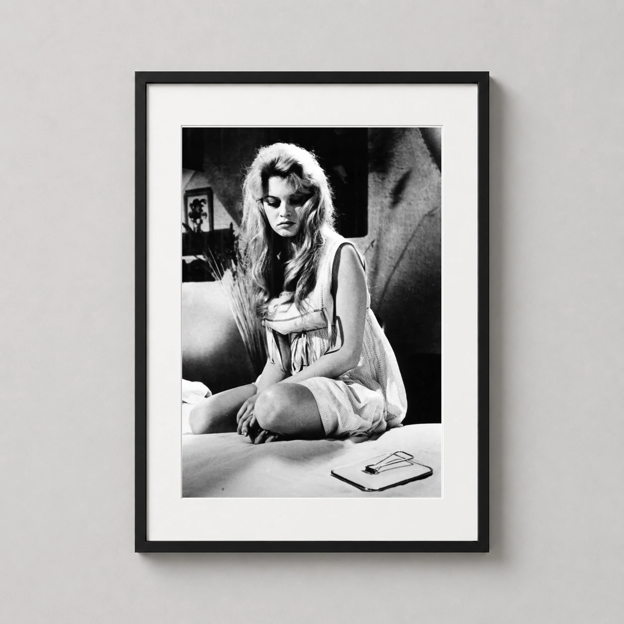 Brigitte Bardot Une Parisienne — pensive Brigitte Bardot sits on a bed in a textured black and white